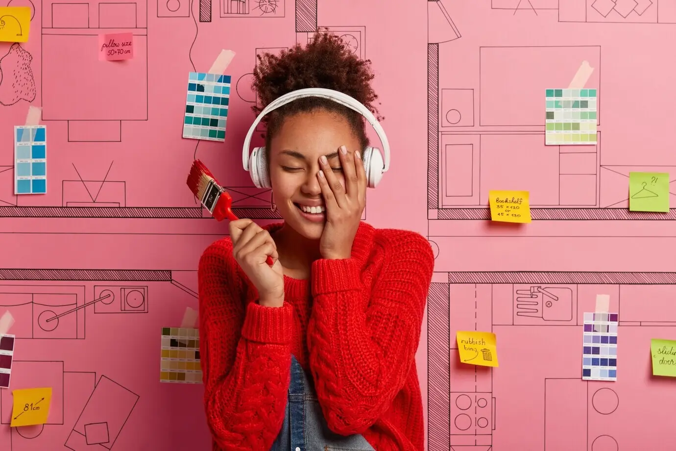 Glückliche junge Designerin plant die Renovierung einer modernen Wohnung.